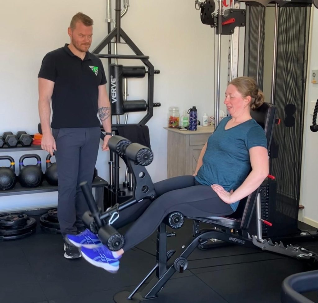 Client training with personal trainer on leg machine